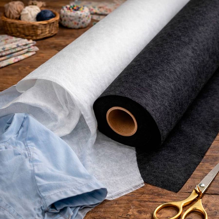 Entretela fina adhesiva por una cara en blanco y negro sobre mesa de costura con prenda de vestir