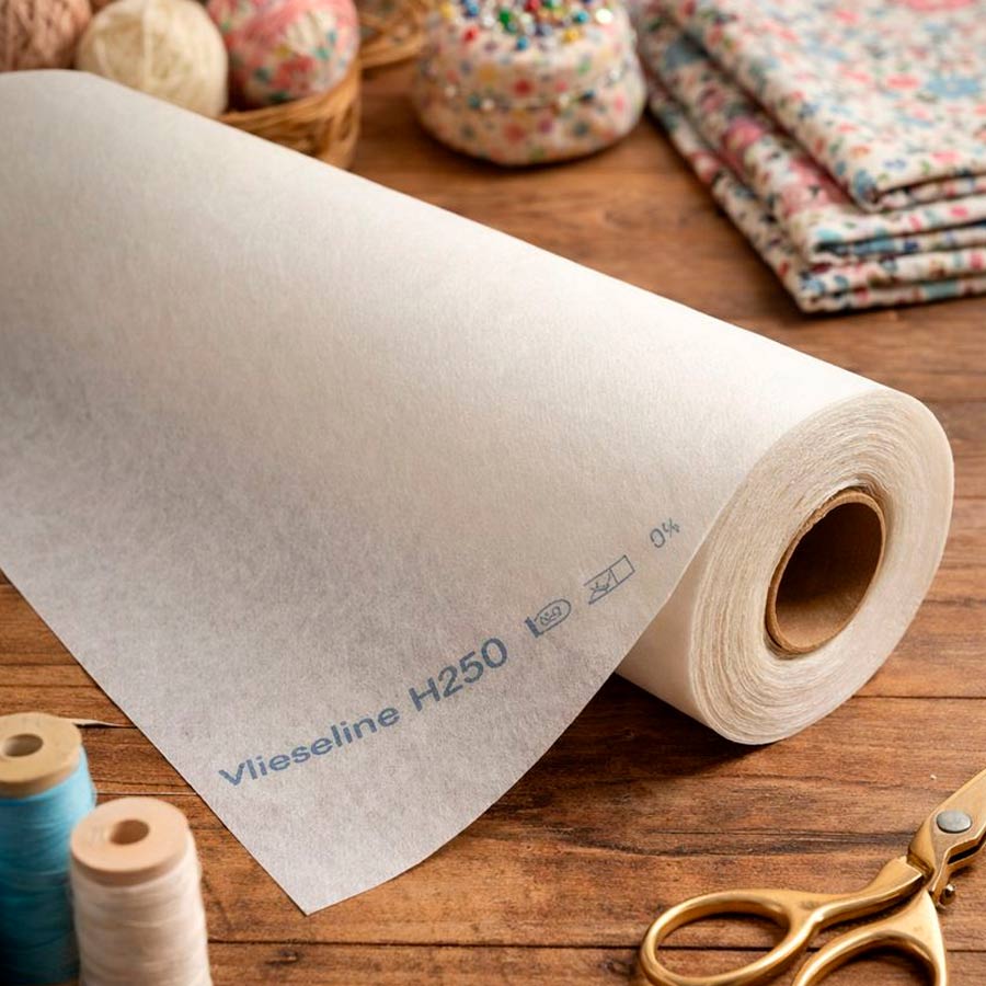 Entretela termoadhesiva Vlieseline H250 sobre mesa de madera con herramientas de costura