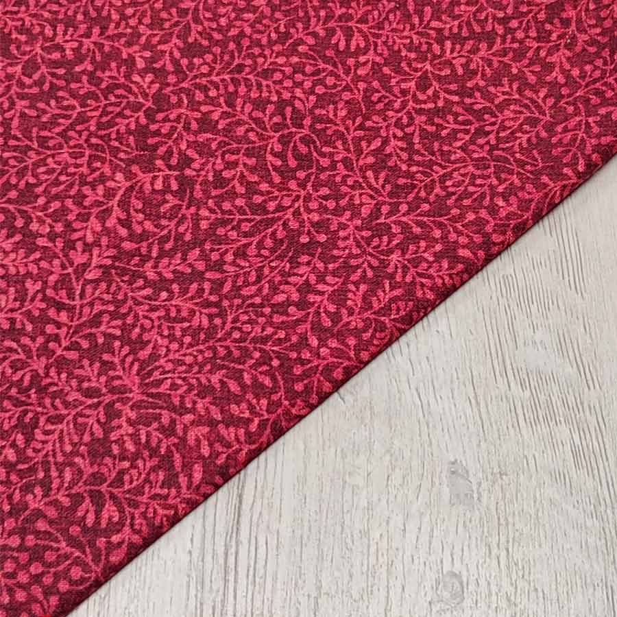 Tela de algodón americano color granate con delicado estampado de ramas y hojas en el mismo tono, ideal para bases de patchwork.